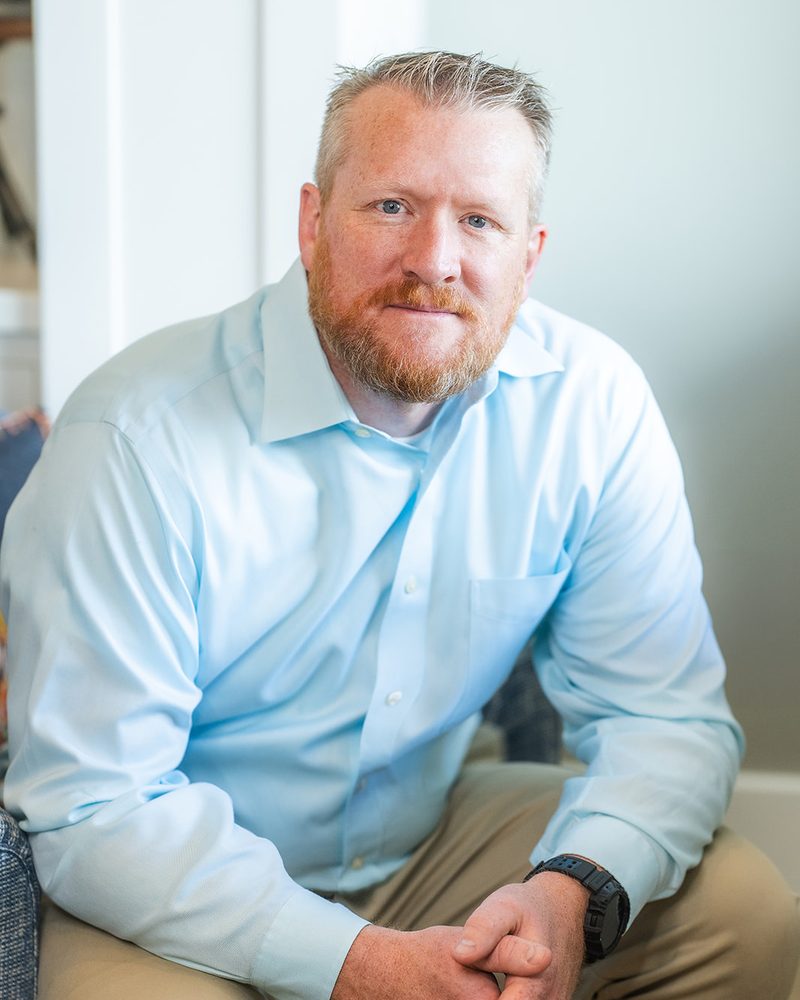Jared Fenn, seated in a light blue shirt, looking at the camera